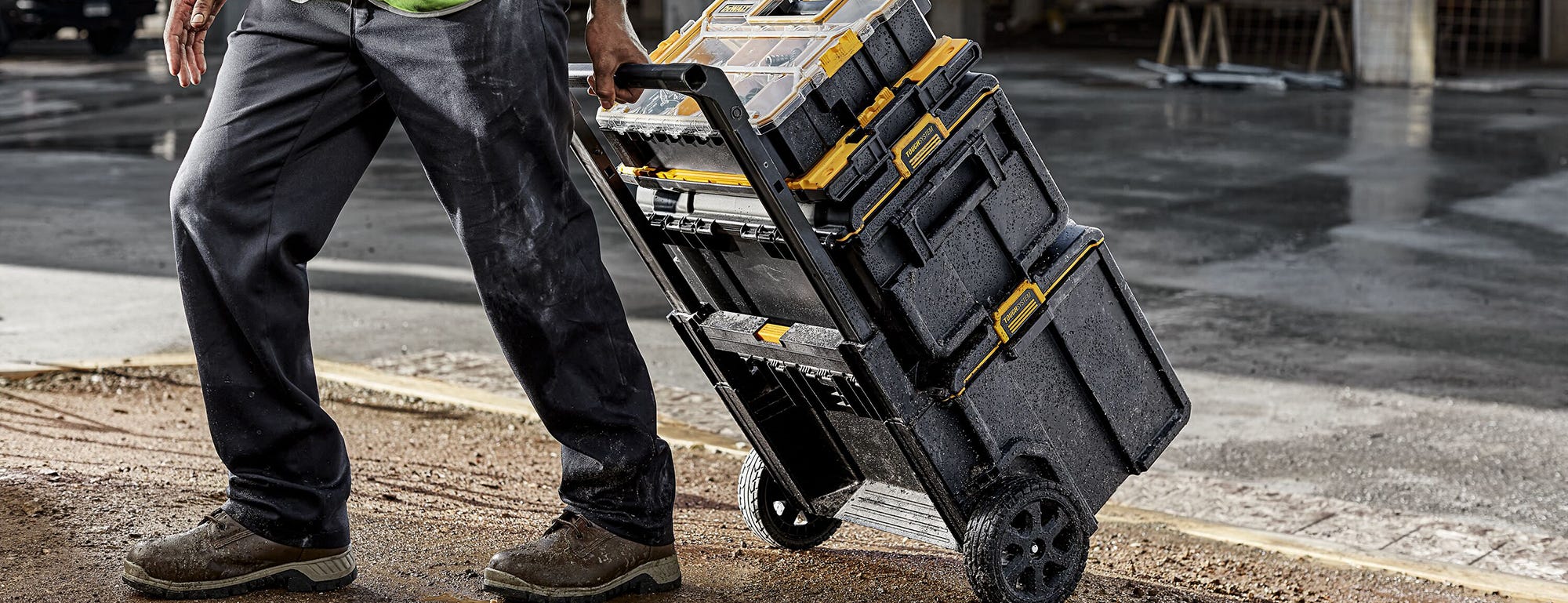 A man on a construction site pulling a DeWalt TOUGHSYSTEM OR TSTAK Series tool box. A man on a construction site pulling a DeWalt TOUGHSYSTEM OR TSTAK Series tool box.