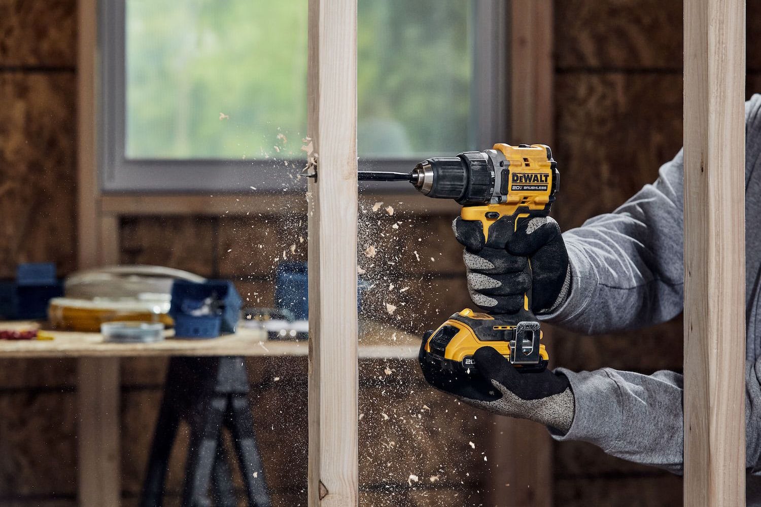 A man using a cordless DeWalt drill to drill through a piece of wood. A man using a cordless DeWalt drill to drill through a piece of wood.